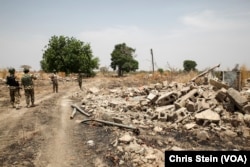 Soldiers walk among the ruins of the Government Secondary School in Chibok, Nigeria, March 25, 2016.