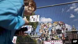 A woman looks at a montage of images of Princess Diana in the shape of a number fifty on fencing outside Kensington Palace in London, which was the residence of the princess, July 1, 2011.