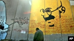 A Palestinian taxi driver prays in front of a section of Israel's separation barrier with a depiction of the late Indian non-violence advocate Mahatma Gandhi (file photo)