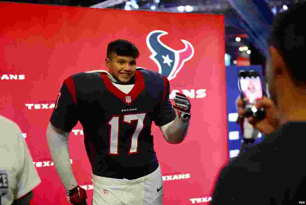 A father takes a photo of his son, who is pretending to be a football player for the local Houston Texans team. The two are at the NFL Experience, a fan festival in downtown Houston before Sunday's Super Bowl game. (B. Allen/VOA)