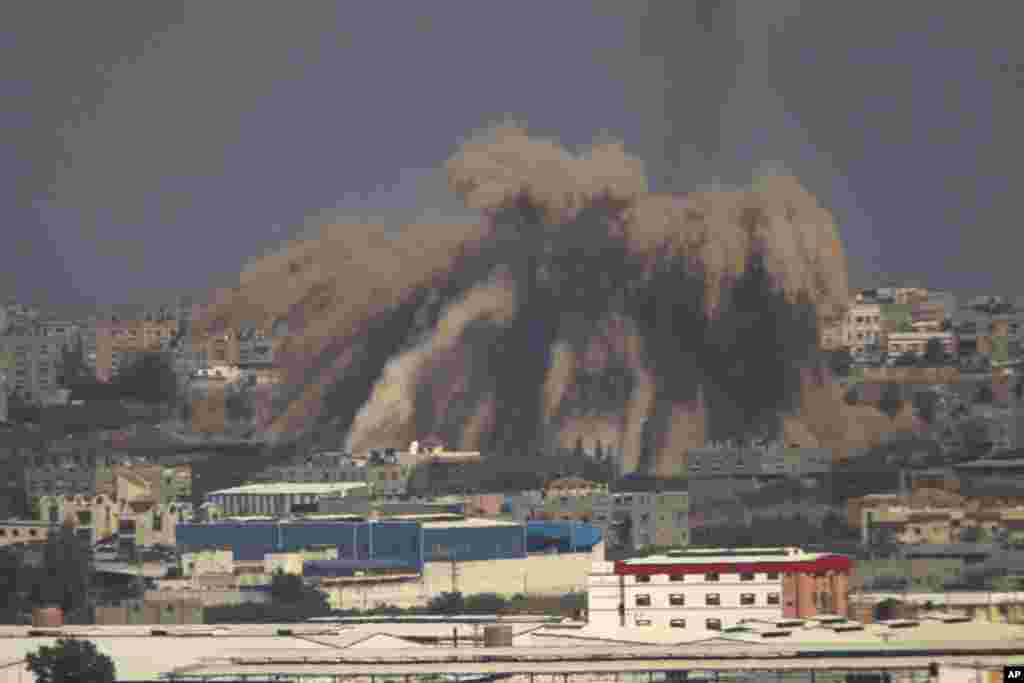 Asap dan puing-puing bangunan menghambur ke atas menyusul serangan Israel di Jalur Gaza (9/7). (AP/Ariel Schalit)