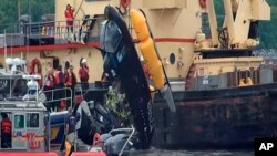 In this image made from video, a crane lifts a helicopter out of the water after it crashed into the Hudson River, May. 15, 2019. in New York. The 34-year-old pilot suffered just a minor hand injury after the hard splashdown. There were no passengers aboard the aircraft. 