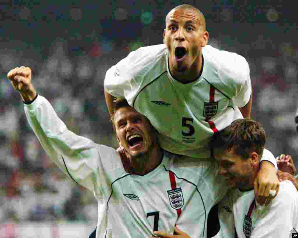 David Beckham, left, Rio Ferdinand, top, and Michael Owen celebrate the team's second goal scored by Owen during the 2002 World Cup second round match against Denmark in Niigata, Japan, June 15, 2002.