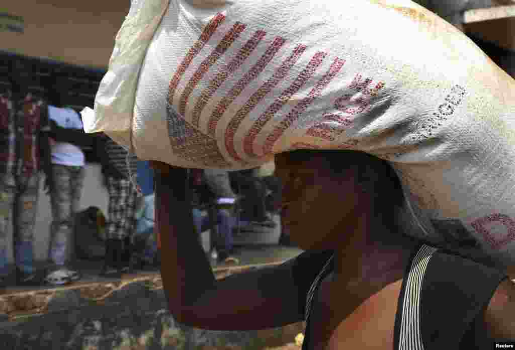 A displaced refugee woman carries a rice bag after receiving it as humanitarian aid at the airport outside the capital Bangui, Jan. 7, 2014.