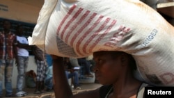 A displaced refugee woman carries a rice bag after receiving it as humanitarian aid at the airport outside the capital Bangui, Jan. 7, 2014.