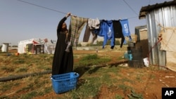 FILE - A Syrian refugee woman hangs laundry at a Syrian refugee camp in the eastern Lebanese town of Majdal Anjar, Lebanon, June 19, 2014.