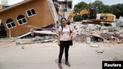 FILE - Ana Maria Hernandez, 37, a clothing salesperson, stands outside her house as it is demolished after an earthquake in Jojutla de Juarez, Mexico, Sept. 30, 2017. 