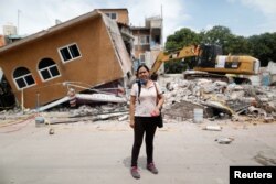 FILE - Ana Maria Hernandez, 37, a clothing salesperson, stands outside her house as it is demolished after an earthquake in Jojutla de Juarez, Mexico, Sept. 30, 2017.