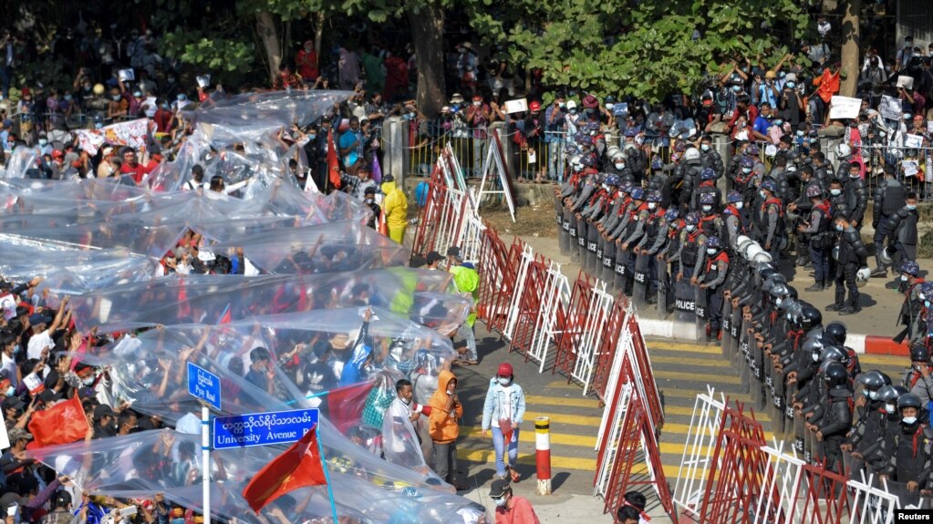 Người biểu tình Myanmar dùng tấm nhựa để tránh vòi rồng trong cuộc biểu tình ngày 9/2/2021.