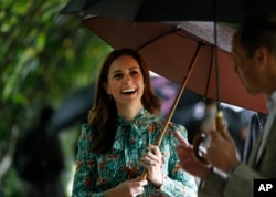 Britain's Prince William and his wife Kate, Duchess of Cambridge smile as they walk through the memorial garden in Kensington Palace. The couple announced that Catherine is pregnant with their third child.