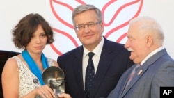 Zhanna Nemtsova, left, the daughter of slain Russian opposition leader Boris Nemtsov stands together with Poland’s President Bronislaw Komorowski center, and former president. Lech Walesa, right, after receiving Poland’s 4 million zlotys ( US $1 million