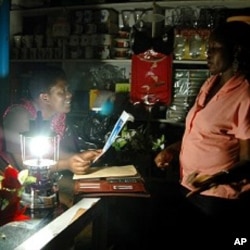 Ugandan women chat in a shop lit by a paraffin lamp in the capital Kampala (file photo)