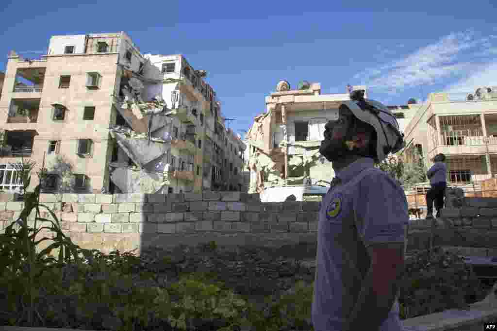 A rescuer looks towards the sky following an airstrike in the rebel-held Ansari district in the northern Syrian city of Aleppo. Syrian and Russian aircraft pounded rebel-held areas, a monitor said, after the army announced a new offensive aimed at retaking all of the divided second city.