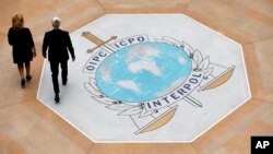 FILE - People walk past the Interpol logo at the headquarters of the international police agency in Lyon, France, Nov.8, 2018. 