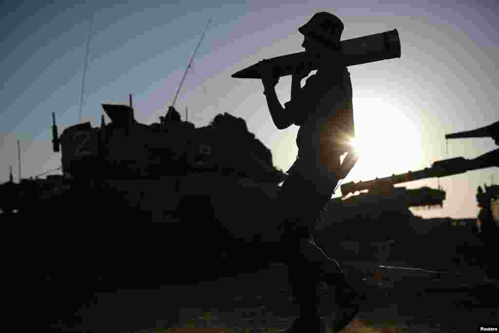 An Israeli soldier carries a tank shell in a staging area near the border with the Gaza Strip, Aug. 7, 2014.