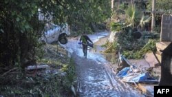 Seseorang melewati jalan yang dilanda banjir dekat sebuah rumah di mana sembilan orang meninggal akibat air meluap dari sungai di Casteldaccia dekat Palermo, Sisilia (4/11).