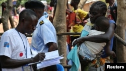 Un responsable de l'OIM enregistre une migrante congolaise arrivée d'Angola à la frontière de Kamako, dans la province du Kasaï en RDC, le 13 octobre 2018.