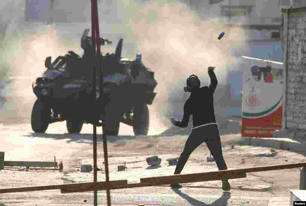 A protester throws a glass bottle containing paint at a riot police armored personnel carrier during anti-government clashes in the village of Sitra, south of Manama, Bahrain.