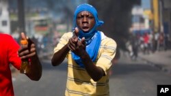 A demonstrator points with his hand, making a pistol, during a protest demanding to know how oil assistance funds have been used by the current and past administrations, in Port-au-Prince, Haiti, Oct. 17, 2018. 