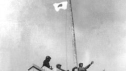 Japanese soldiers raise their flag over the central government building in Nanking after seizing the city in 1937