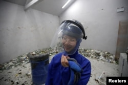 High school student Qiu Siyu, wearing protective gear, reacts after smashing wine bottles in an anger room in Beijing, China January 12, 2019. (REUTERS/Jason Lee)