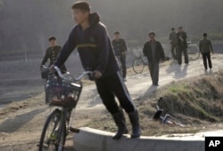 Some North Korean men walk while others push bicycles along a highway at the end of a work day in Pyongyang, April 11, 2017, North Korea. North Korea will mark the 105th anniversary of the birth of the late leader Kim Il Sung on April 15.