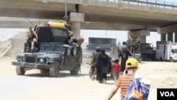 Sejumlah keluarga berlindung di bawah jembatan tempat mereka bertemu dengan truk dan bus yang mengangkut orang-orang sipil ke kamp-kamp, sementara tentara melakukan perjalanan yang berlawanan ke garis depan di Mosul, Irak, 4 Juni 2017. (H. Murdock / VOA)