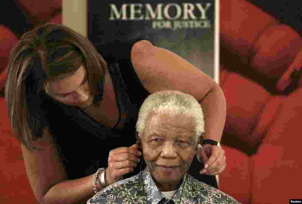 L&#39;ancien président sud-africain Nelson Mandela assisté par Zelda la Grange qui l&#39;aide à ajuster son aide auditive lors de son acceptation de collections historiques des Archives nationales à la base Mandela à Houghton, le 28 Novembre 2008.