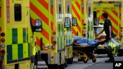 FILE - A patient is pushed on a trolley after arriving in an ambulance outside the Royal London Hospital in the Whitechapel area of east London, Thursday, Jan. 6, 2022. 