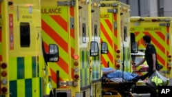 FILE - A patient is pushed on a trolley after arriving in an ambulance outside the Royal London Hospital in the Whitechapel area of east London, Thursday, Jan. 6, 2022. 