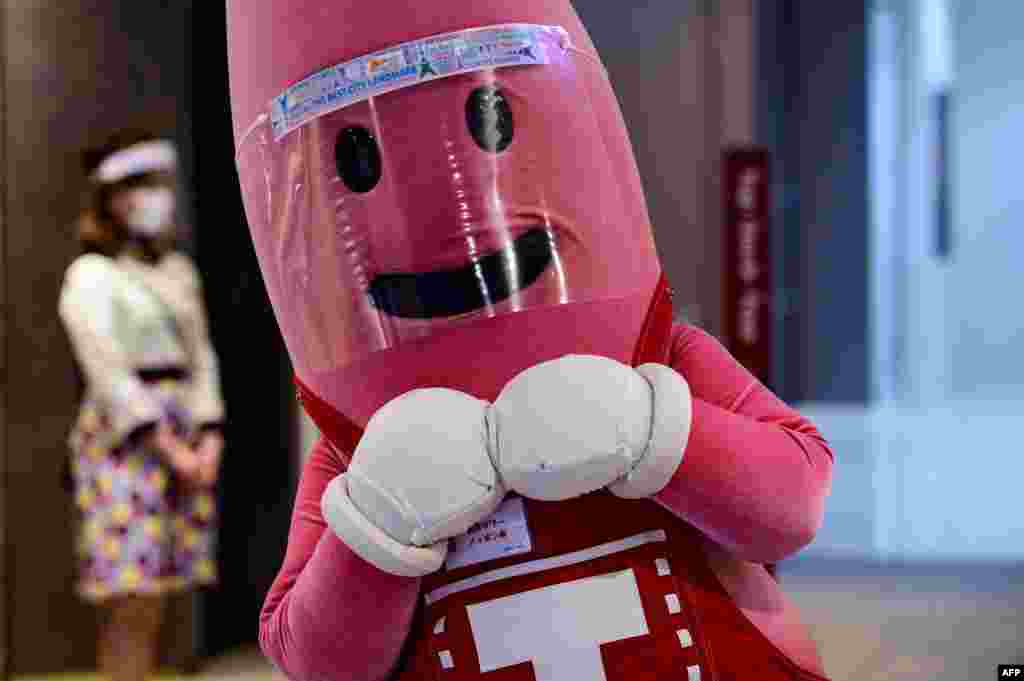 A person dressed as the mascot of Tokyo Tower wears a face shield while waiting to greet patrons at the entrance of the 332.9 meter (1,092 foot) high tower, as the city&#39;s landmark reopened following coronavirus lockdown.