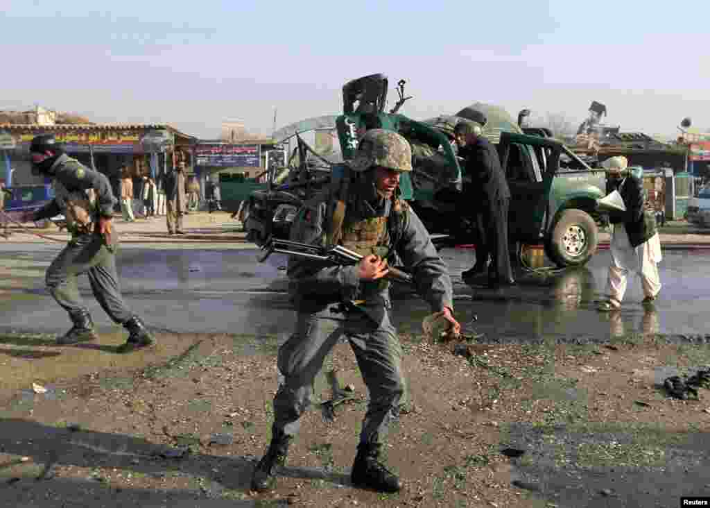 Afghan police inspect the site of the bombing of a police car that killed two policemen and wounded five others in Jalalabad, Dec. 17, 2014. 