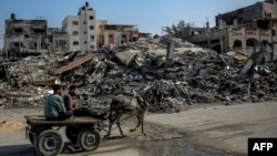 Palestinos montan una carreta tirada por un burro junto a edificios destruidos durante los ataques israelíes en Beit Lahia, en el norte de Gaza. Foto tomada el 26 de febrero de 2024, en medio de continuas batallas entre Israel y el grupo militante palestino Hamás.