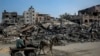 26일 가자지구 북부 이스라엘군 공습 잔해 곁에서 팔레스타인인들이 당나귀 수레를 타고 이동하고 있다. 