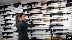 Gun shop owner Tiffany Teasdale-Causer returns a Ruger AR-15 semi-automatic rifle, the same model, though in gray rather than black, used by the shooter in a Texas church massacre two days earlier, to it's place on a wall with dozens of other semi-automat