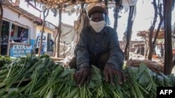 Un vendedor exhibe verduras en su puesto, mientras usa una mascarilla para protegerse contra el coronavirus, en un mercado de productos agrícolas en Lilongwe , Malawi, el 4 de mayo de 2020.