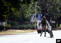 An armed soldier turns away a vehicle during lockdown in Harare, Zimbabwe, April 13, 2020, in an effort to curb the spread of the coronavirus.
