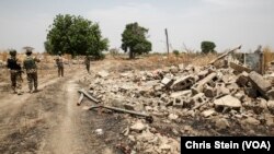 Soldiers walk among the ruins of the Government Secondary School in Chibok, Nigeria, March 25, 2016.