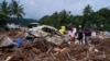 Anggota tim penyelamat berdiri di samping mobil yang rusak akibat tanah longsor pada hari kedua pencarian korban pada 31 Juli 2024, setelah tanah longsor menerjang distrik Wayanad, negara bagian Kerala, India. (Foto: AP/Rafiq Maqbool) 