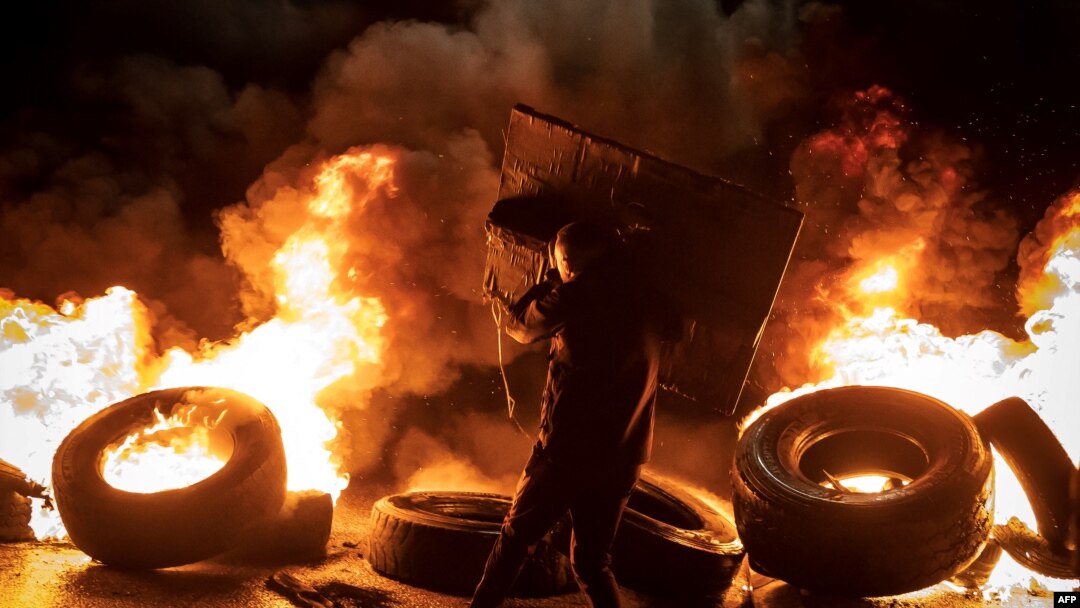 A protester walks near burning tires in the occupied West Bank on Nov. 27, 2023, ahead of an expected release of Palestinian prisoners in exchange for Israeli hostages held by Hamas.