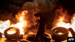 A protester walks near burning tires in the occupied West Bank on Nov. 27, 2023, ahead of an expected release of Palestinian prisoners in exchange for Israeli hostages held by Hamas.