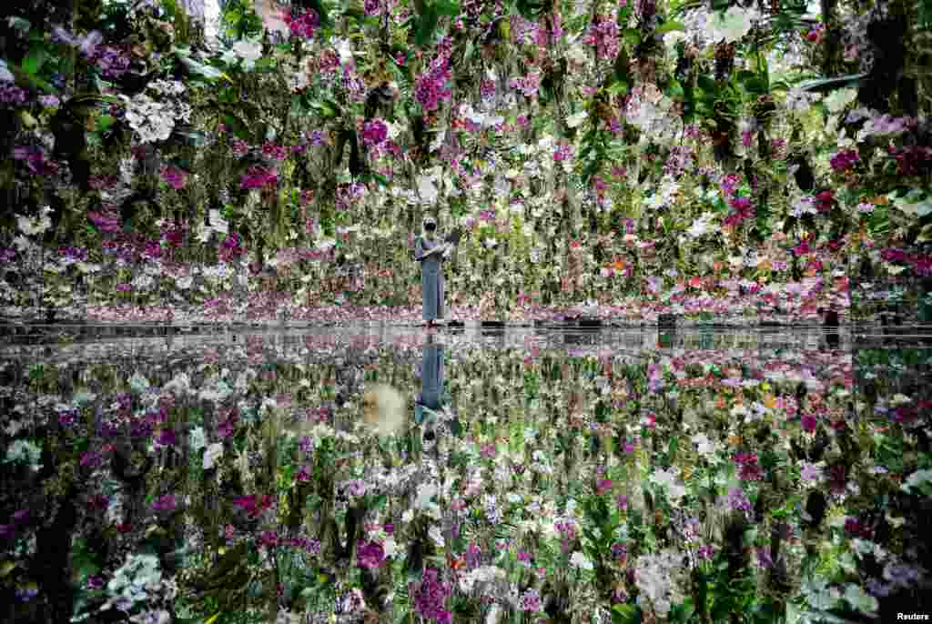 A teamLab staff member works inside the &quot;Floating Flower Garden&quot;, which consists of a three-dimensional mass of flowers, at teamLab Planets in Tokyo, Japan.