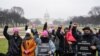 FILE - Service industry workers hold up signs during a rally in support of the Raise the Wage Act, which includes a $15 minimum wage for tipped workers, at the National Mall, in Washington, Jan. 25, 2021.