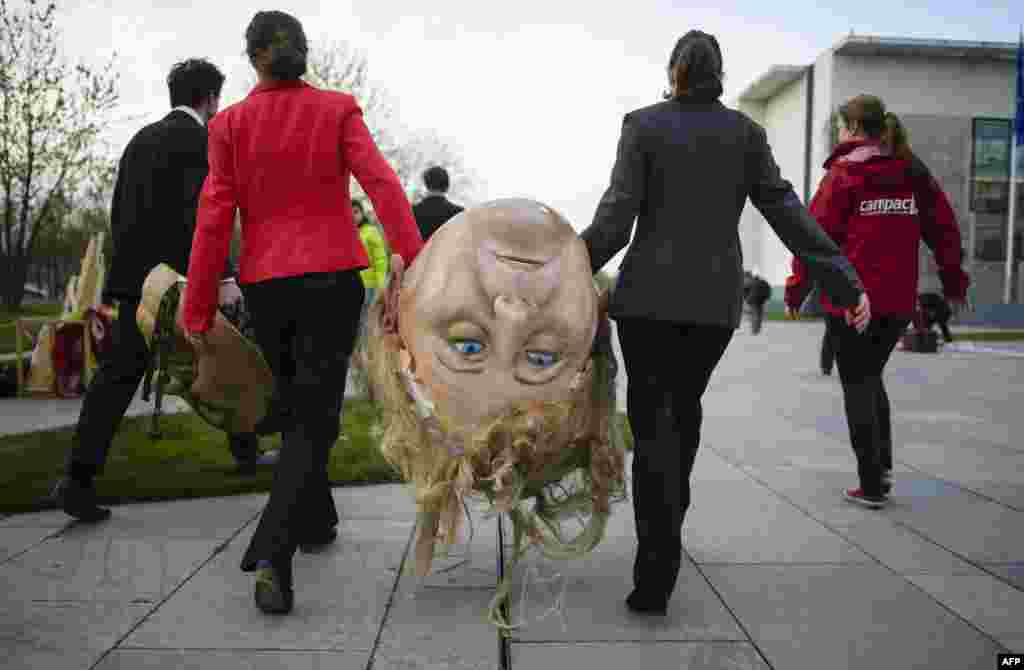 Activistas do BUND e associações ambientais Campact transportam a &quot;cabeça&quot; da chanceler alemã, Angela Merkel antes da manifestação contra a reforma das Fontes de Energia Renováveis em Berlin.