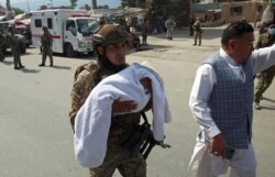 An Afghan security officer carries a baby after gunmen attacked a maternity hospital, in Kabul, May 12, 2020.