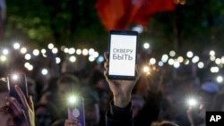 Demonstrators wave their cellphones as they protest plans to construct a cathedral in a park in Yekaterinburg, Russia, May 15, 2019. The words on the phone pictured say, "Park has to be!"
