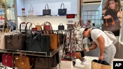 ARCHIVO - Un compador revisa carteras de mujer en la tienda Macy's de Nueva York el 24 de noviembre de 2024.