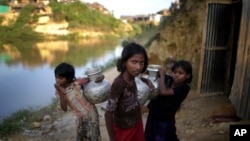 FILE - Rohingya girls carry water pots at Kutupalong refugee camp in Bangladesh, Nov. 19, 2017. Women and girls in this and other camps are often targets of traffickers.