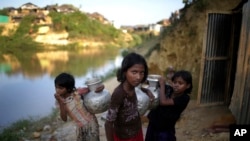 Gadis-gadis Rohingya membawa kendi air di kamp pengungsi Kutupalong di Bangladesh, 19 November 2017. (Photo: (AP/Wong Maye)