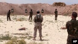 FILE - Syrian Arab trainees practice firing small arms at an undisclosed training range in northern Syria, May 21, 2016. 